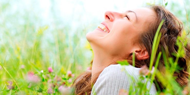 Ragazza di buonumore in un campo di fiori in primavera