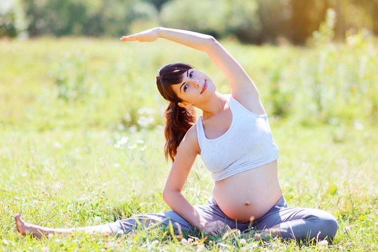 Donna incinta serena che fa yoga all'aria aperta