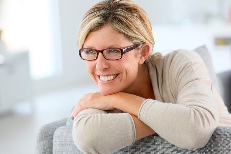 Donna in menopausa sorride seduta sul divano