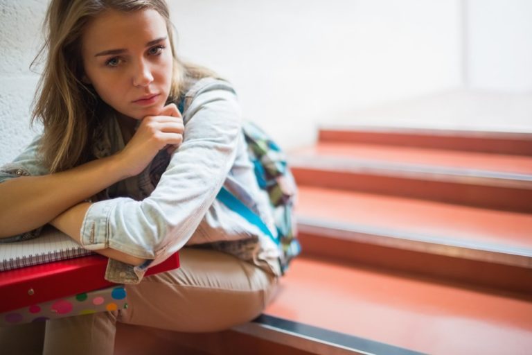 Studentessa seduta sugli scalini con malumore per il rientro a scuola