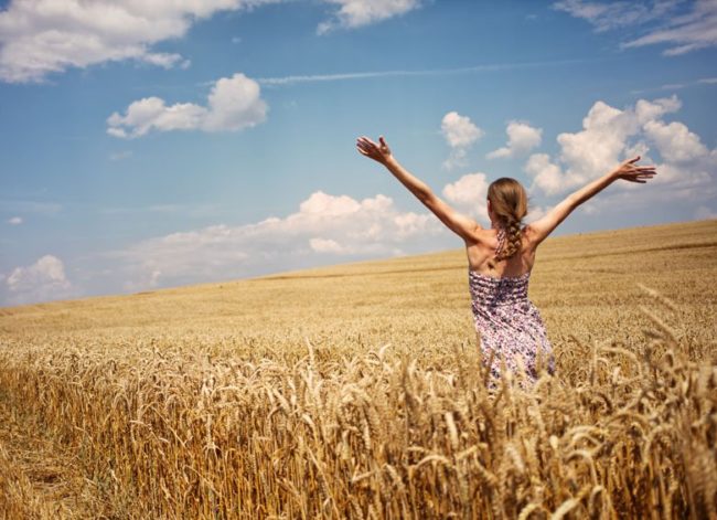 Ragazza apre le braccia in un campo di grano