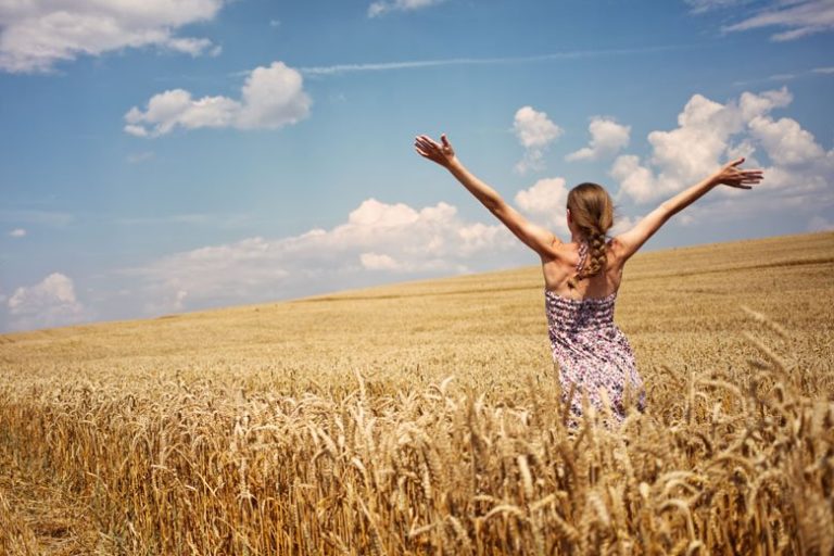 Ragazza apre le braccia in un campo di grano