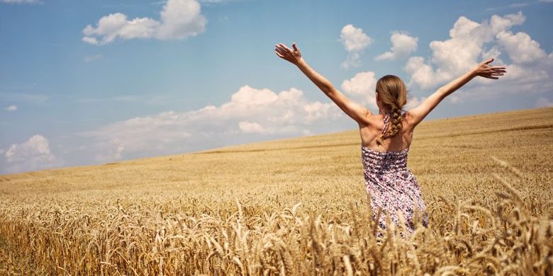 Ragazza apre le braccia in un campo di grano