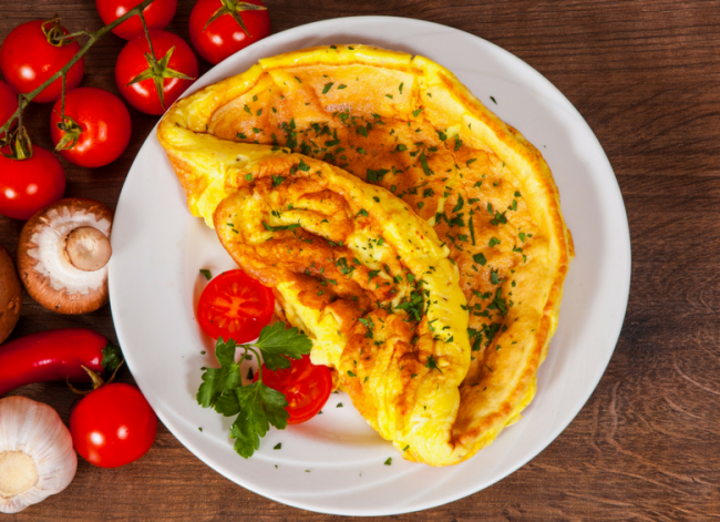 Omelette servita su un ipatto con prezzemolo e pomodorini