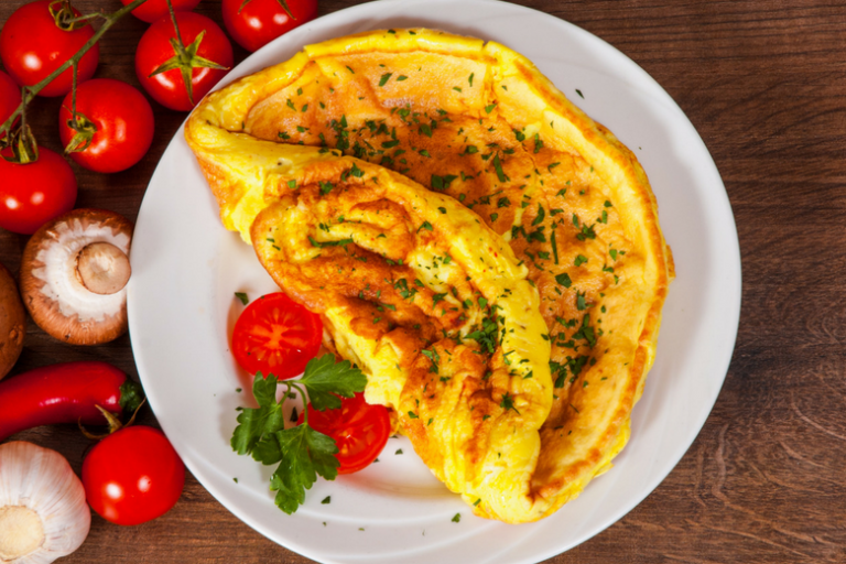 Omelette servita su un ipatto con prezzemolo e pomodorini