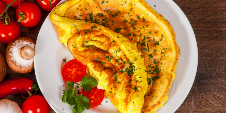 Omelette servita su un ipatto con prezzemolo e pomodorini